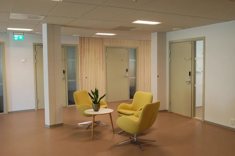 Et rom med gule stoler og et bord med en plante på