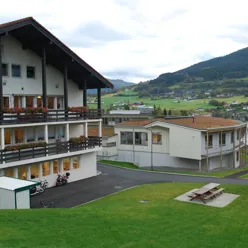 A building with a lawn in front of it and a hill in the background