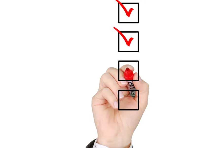 Hand som krysser av i sjekkboksar